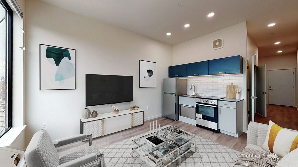 Modern living room with kitchen area, TV, artwork, and furniture.