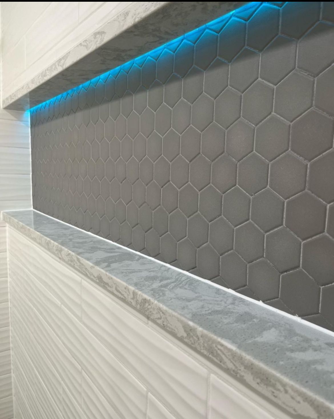 A bathroom with a honeycomb tile wall and a marble counter top.