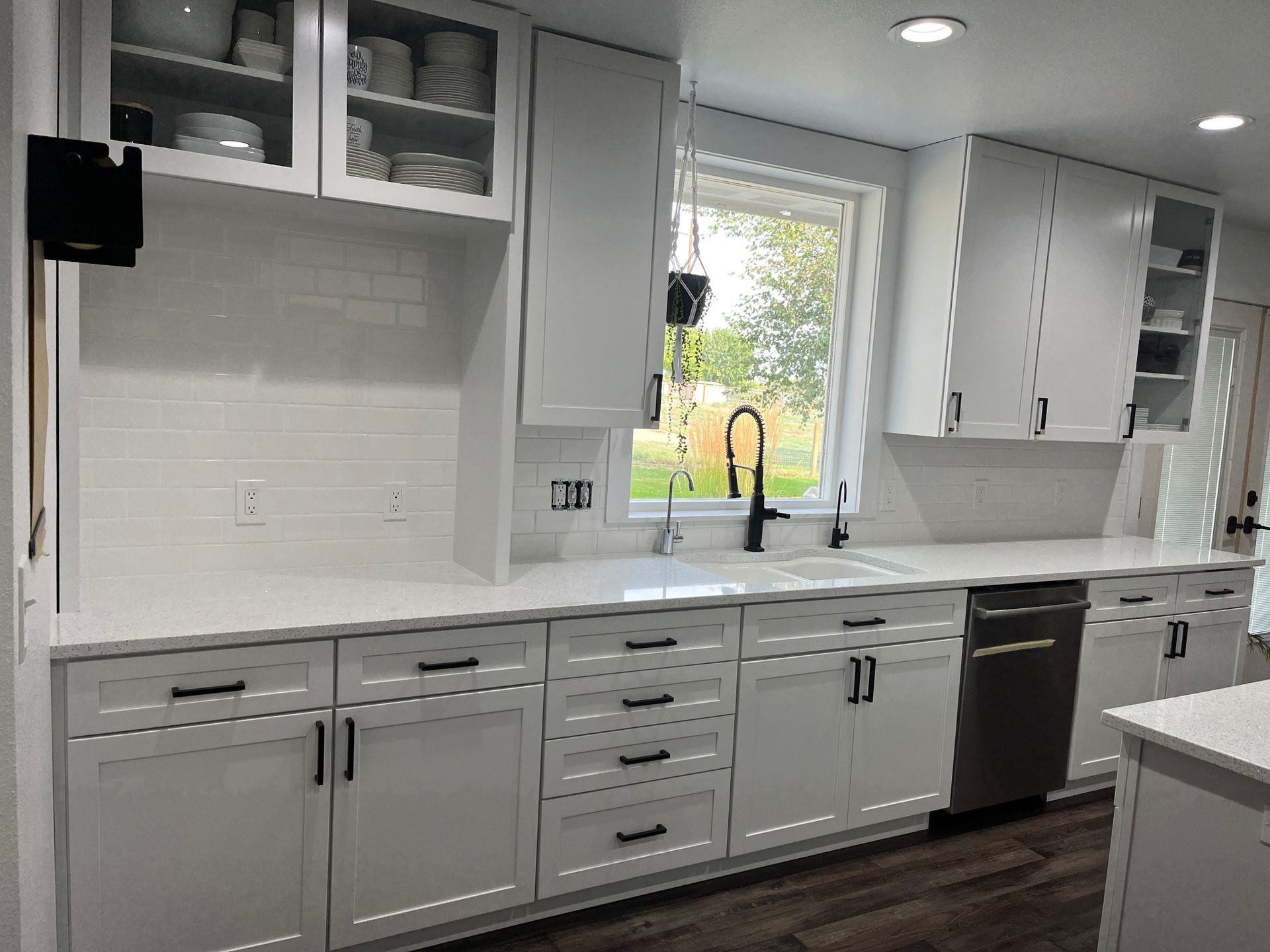 A kitchen with gray cabinets, white counter tops, and a large island.