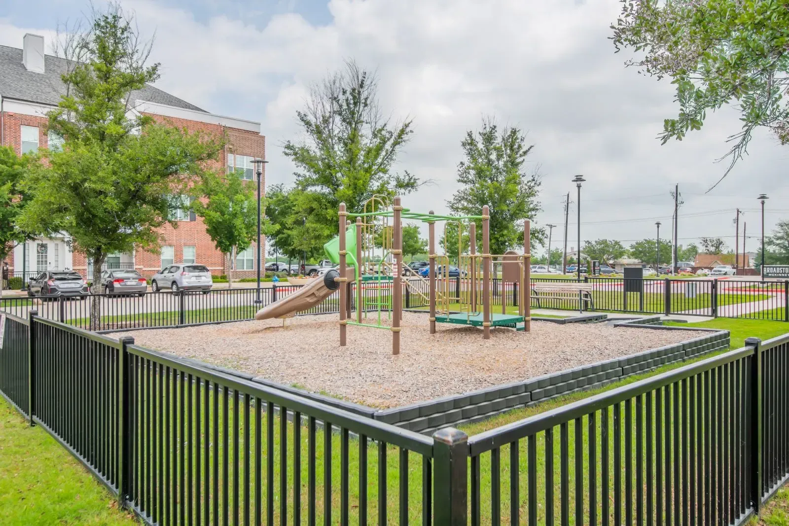 Playground equipment inside a fenced community courtyard of an apartment complex.