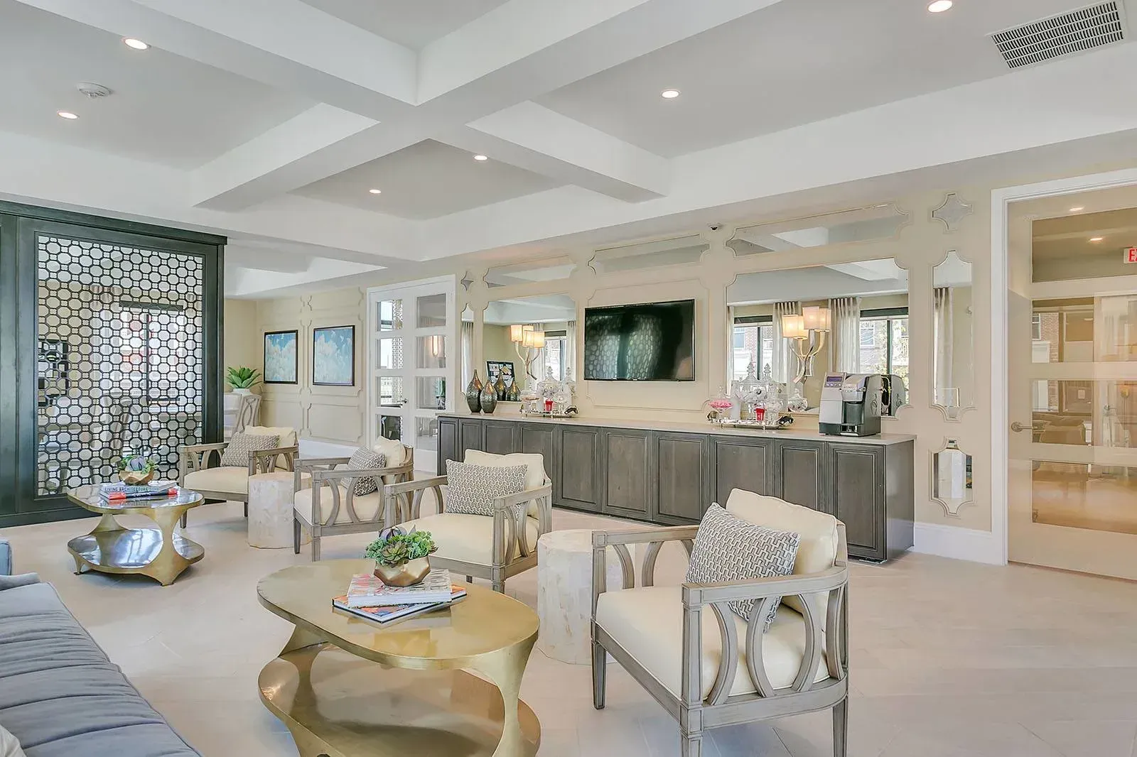 Bright lobby lounge with seating, a wall-mounted TV, and a coffee station.