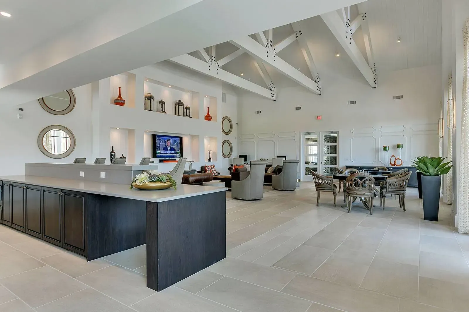 Spacious modern community lounge with seating areas, a long reception desk, and wall decor.