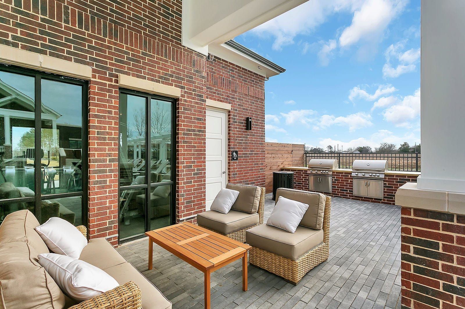 Outdoor brick patio with wicker seating and built-in grills.