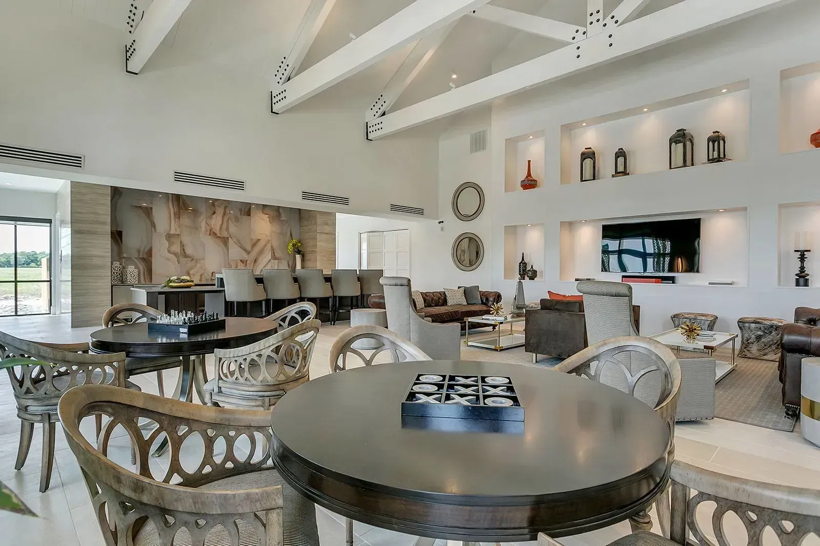 Spacious modern resident lounge with round tables, seating, and wall display.