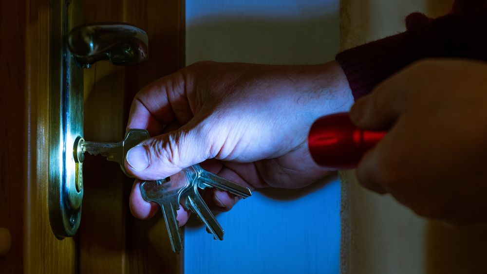 A Person Is Holding A Flashlight And Keys In Their Hand — Troy Cummings Locksmith In Bungalow, QLD