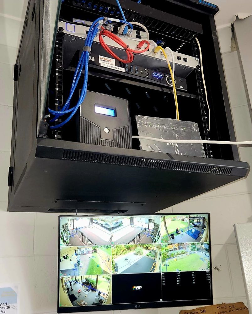 A TV Is Hanging On A Wall Next To A Server Rack — Troy Cummings Locksmith In Bungalow, QLD