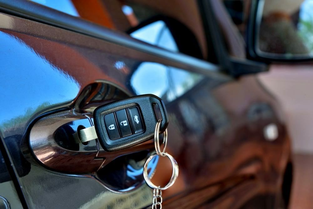 A Car Key Is Sticking Out Of The Door Of A Car — Troy Cummings Locksmith In Tully, QLD