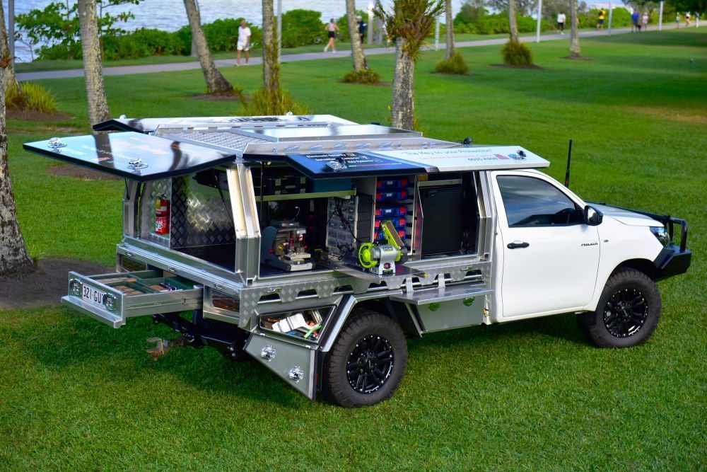 A White Truck With A Canopy Is Parked In A Grassy Field — Troy Cummings Locksmith In Weipa, QLD