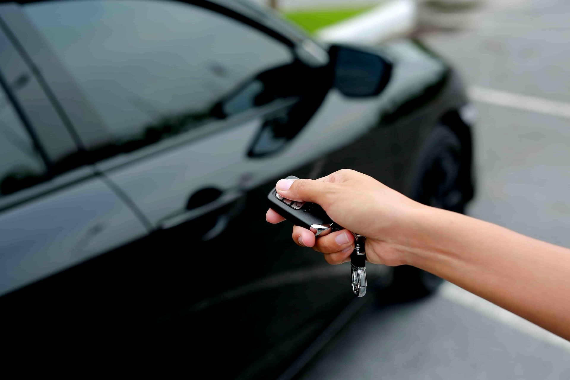 A Person Is Holding A Remote Control In Front Of A Car — Troy Cummings Locksmith In Mossman, QLD
