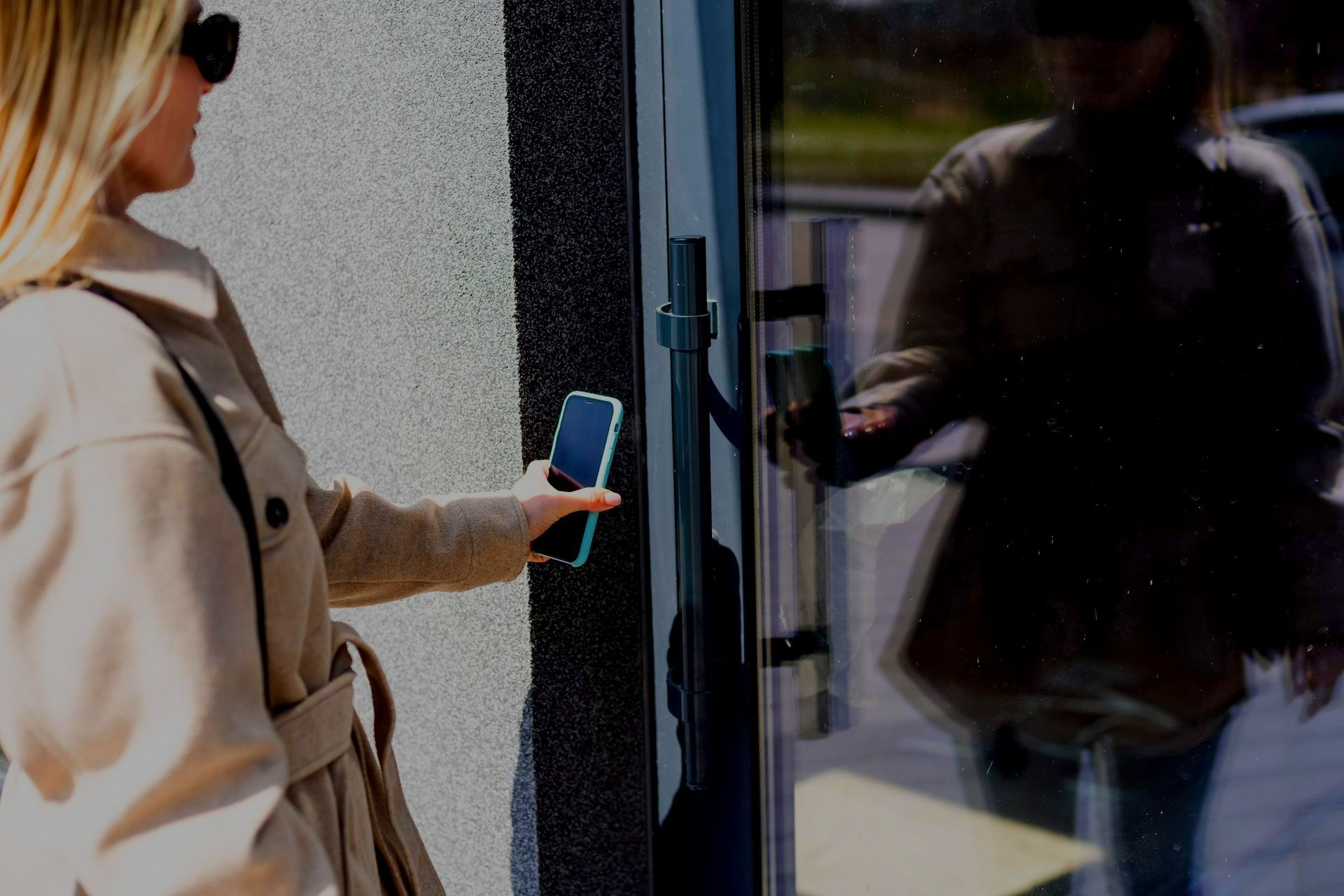 A Woman Is Using A Smart Phone To Open A Door — Troy Cummings Locksmith In Bungalow, QLD