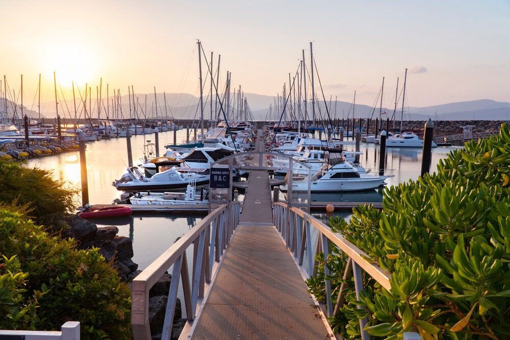 A Dock Leading To A Marina Filled With Boats At Sunset — Troy Cummings Locksmith In Port Douglas, QLD
