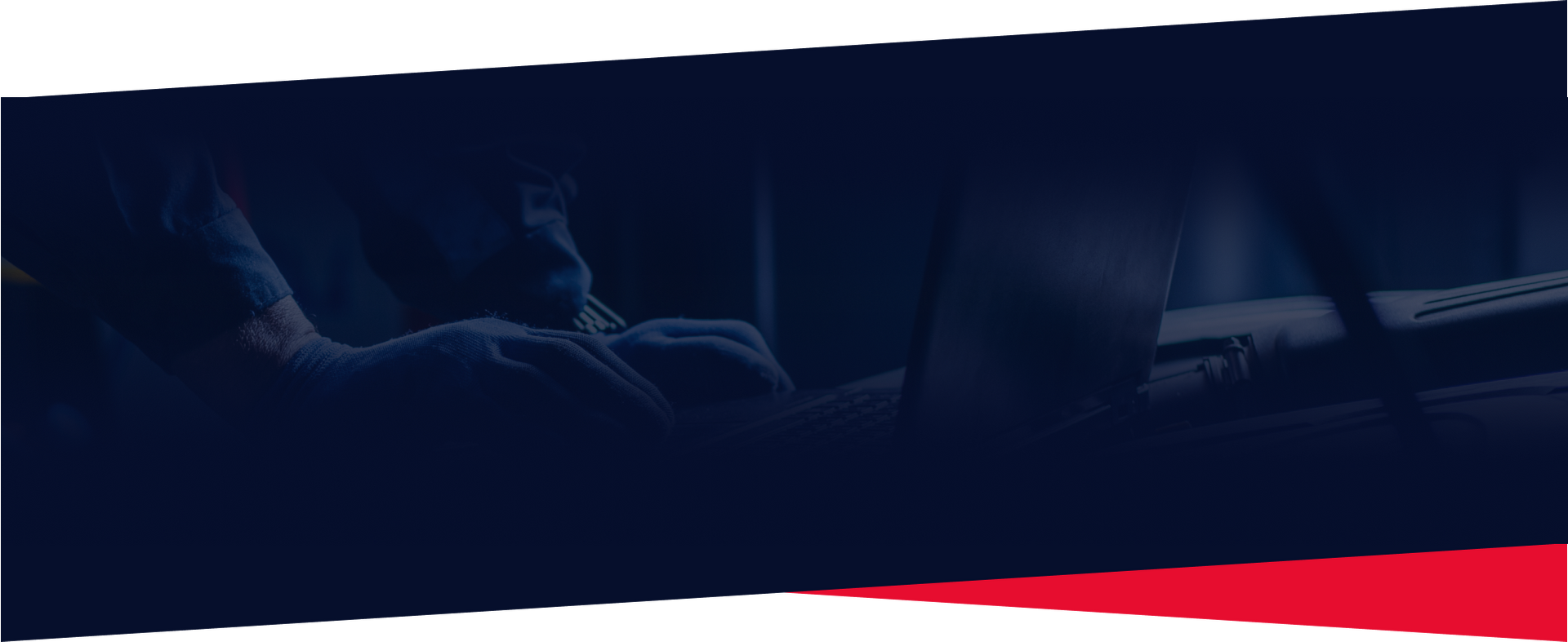 Person working on a laptop, hands on the keyboard in a dark room.