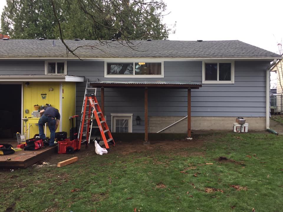 A man is working on a porch in front of a house.