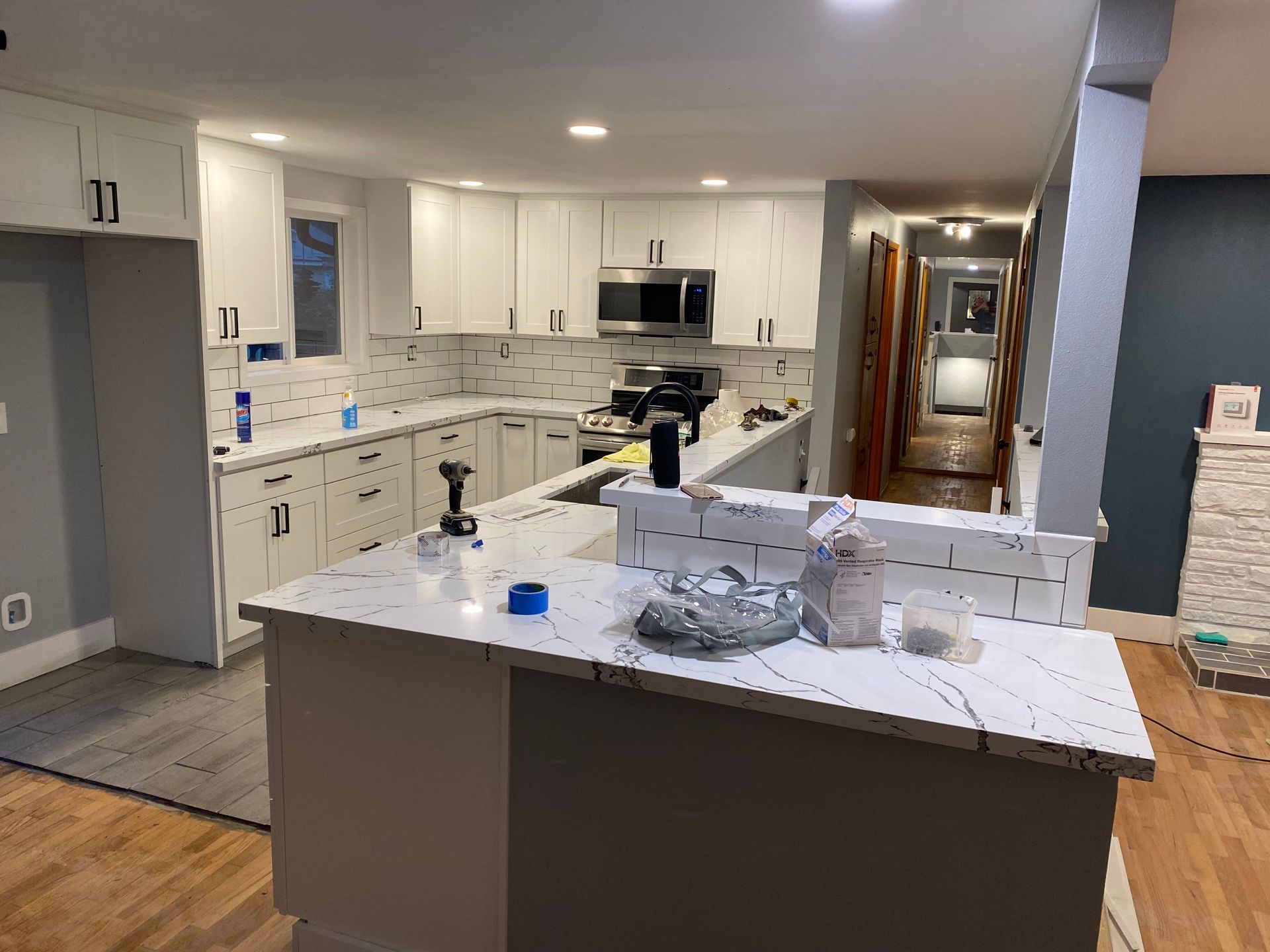 A kitchen with white cabinets and a marble counter top is being remodeled.