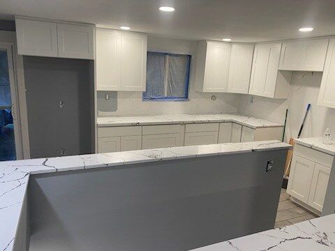 A kitchen with white cabinets and white counter tops is being remodeled.