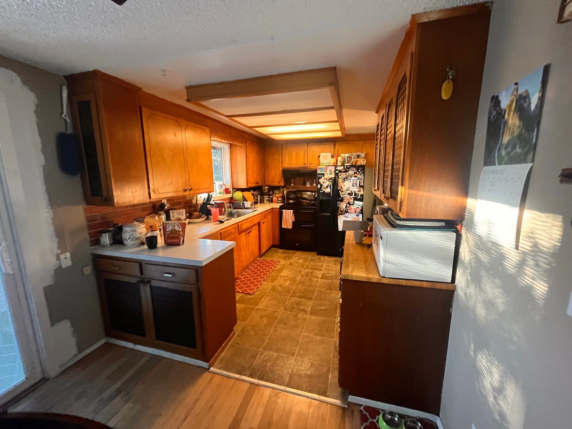 A kitchen with wooden cabinets and a black refrigerator.