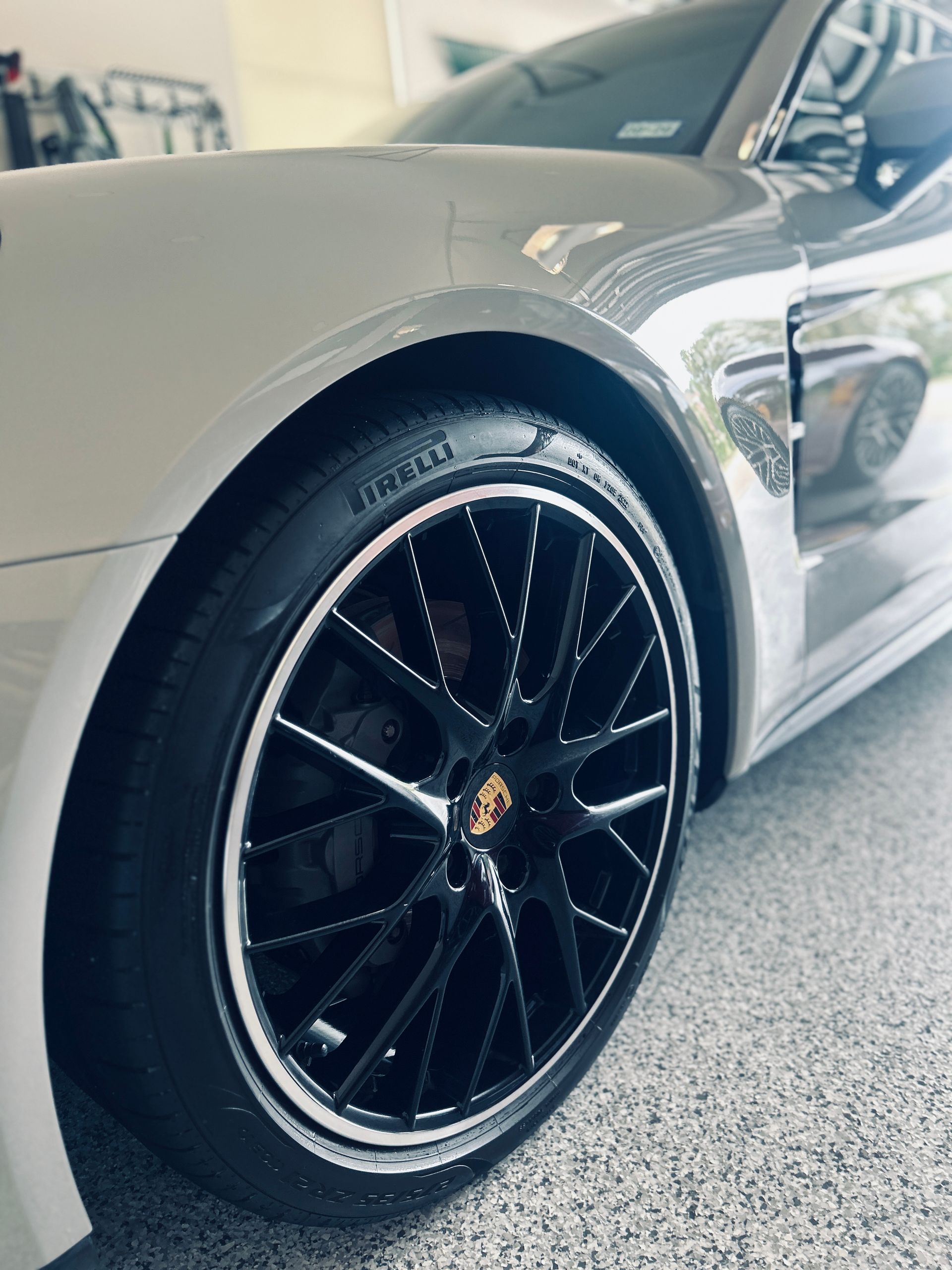 Silver Porsche car with black rims. Close-up view of tire and wheel.