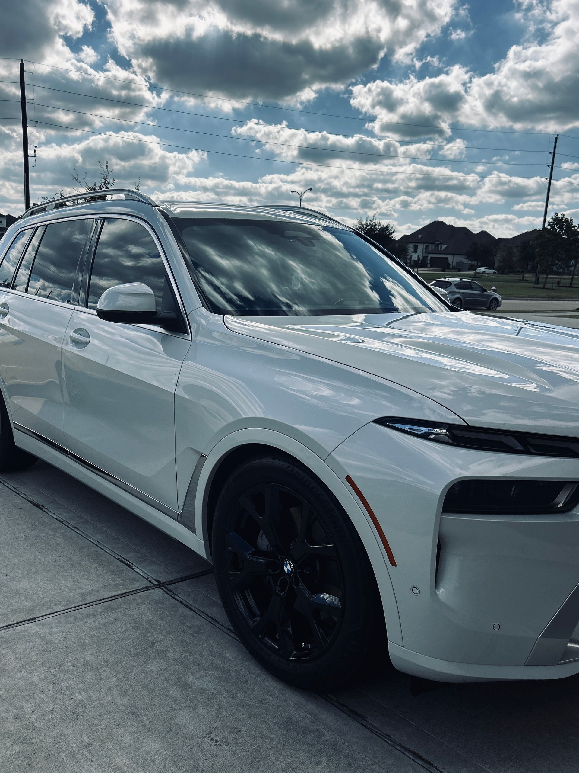 White SUV with black wheels parked outside on a cloudy day.