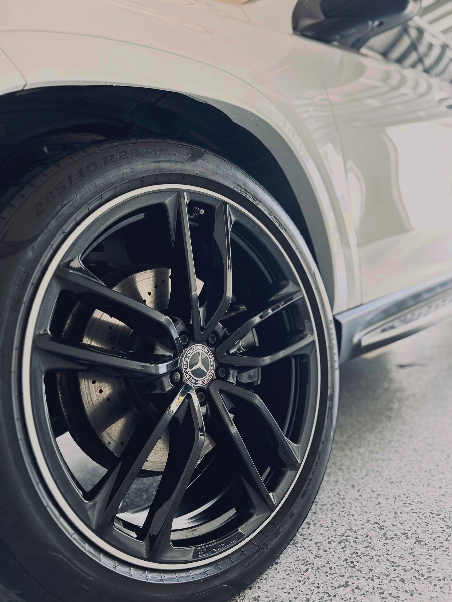 Black alloy wheel with Mercedes logo on a white car.
