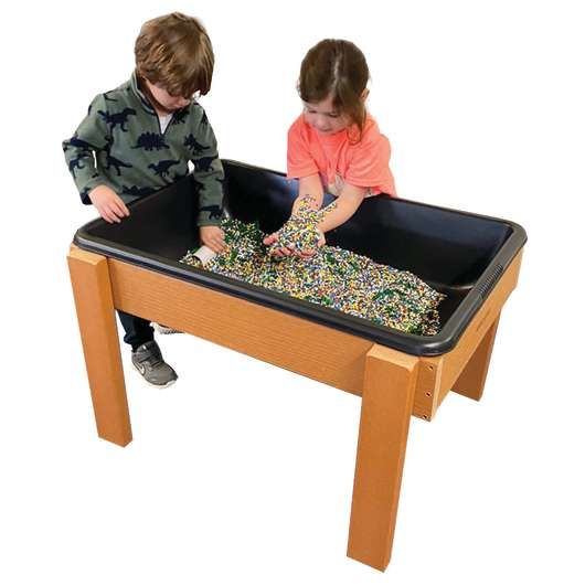 A boy and a girl are playing with sand on a table