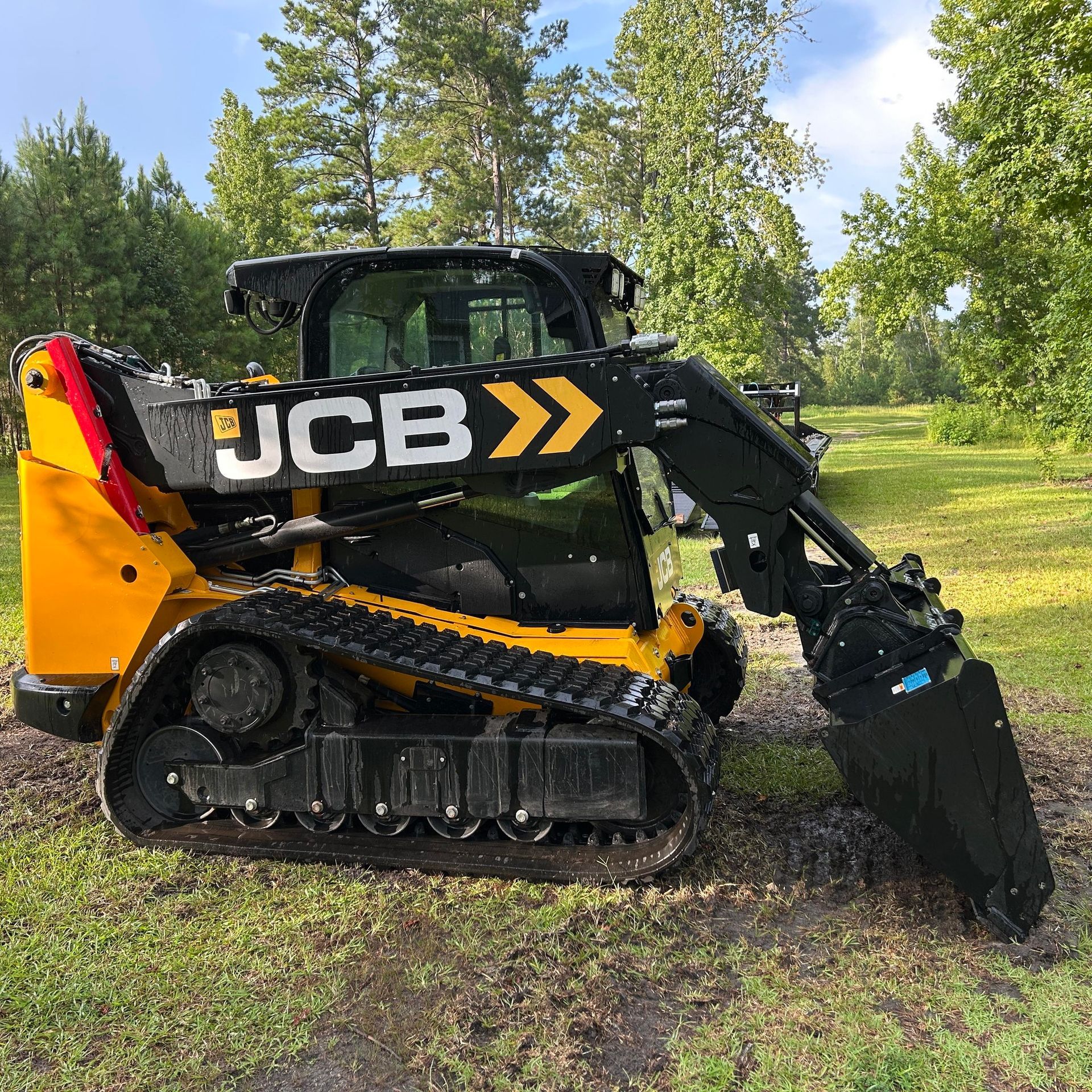 Yellow and black JCB tracked skid steer loader outdoors.
