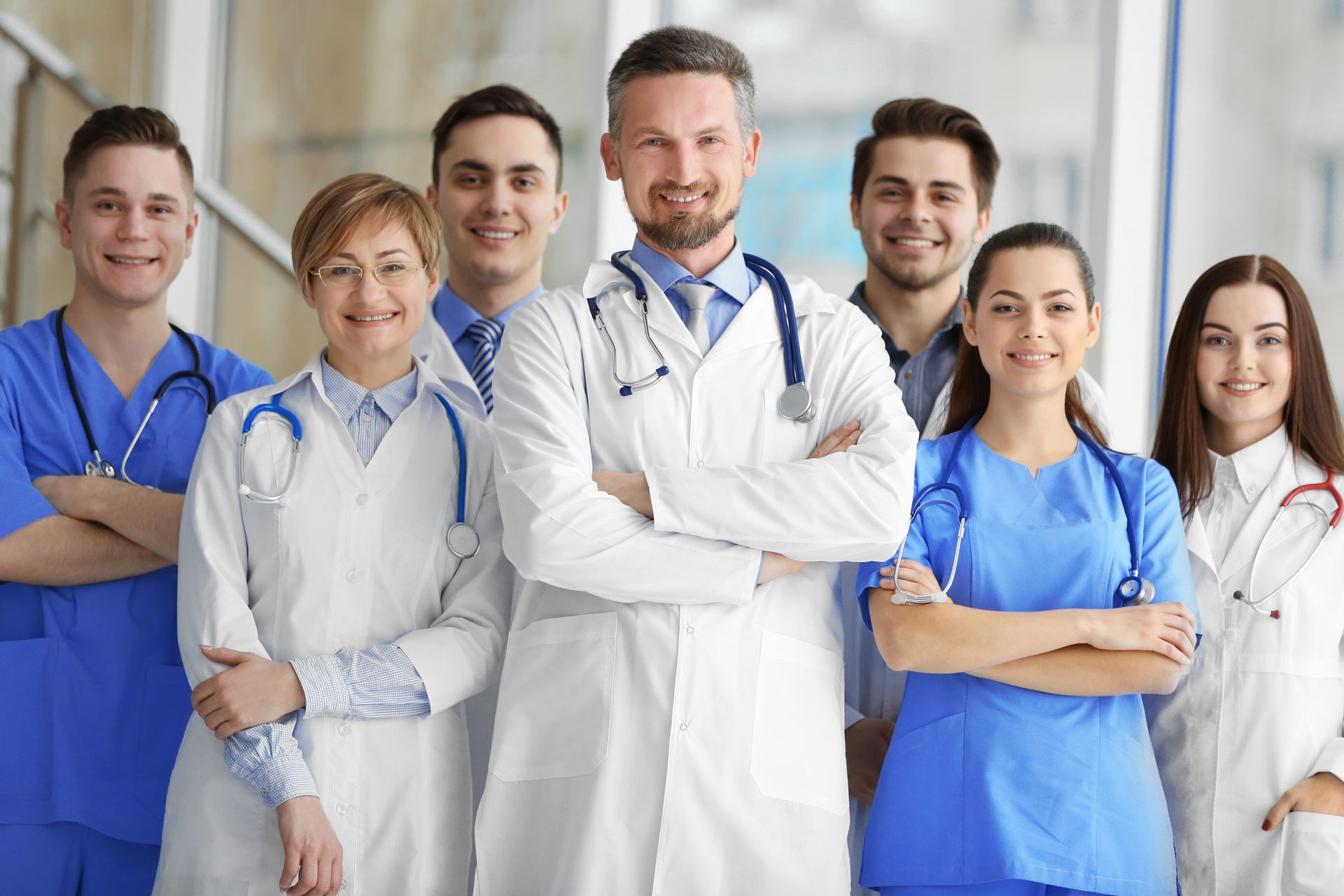 Doctor in white coat checks patient's pulse on their wrist, using stethoscope.