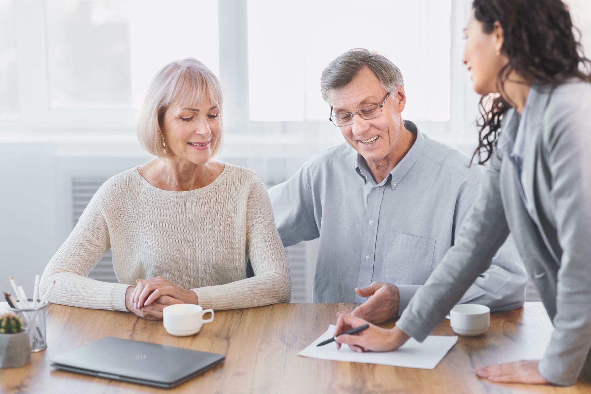 Senior couple reviewing documents with a professional at a table.