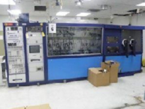 A large machine is sitting in a room with boxes on the floor