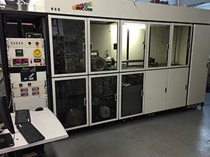 A large machine is sitting in a room next to a desk and a computer.