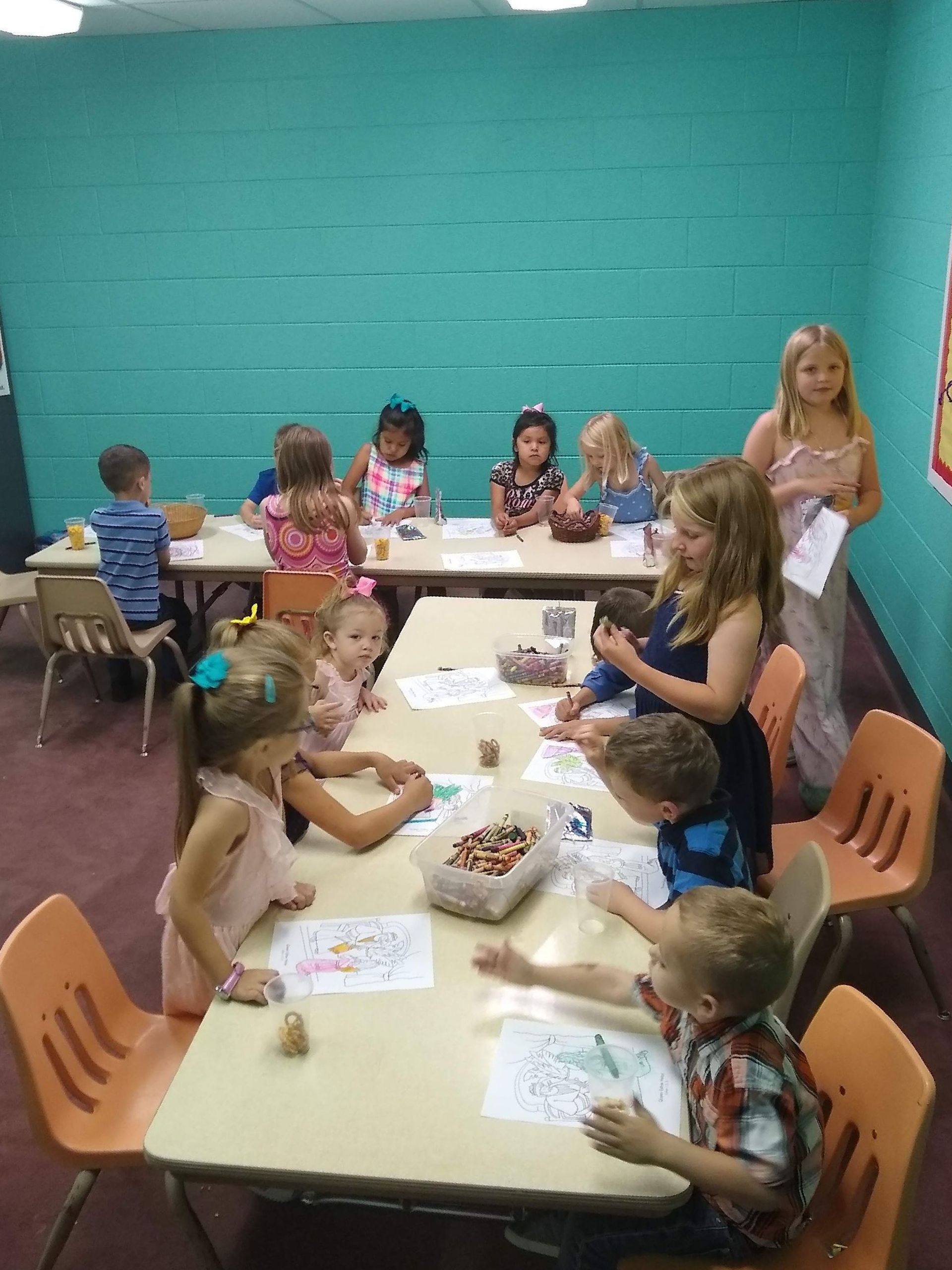 A group of children are sitting at tables in a room.