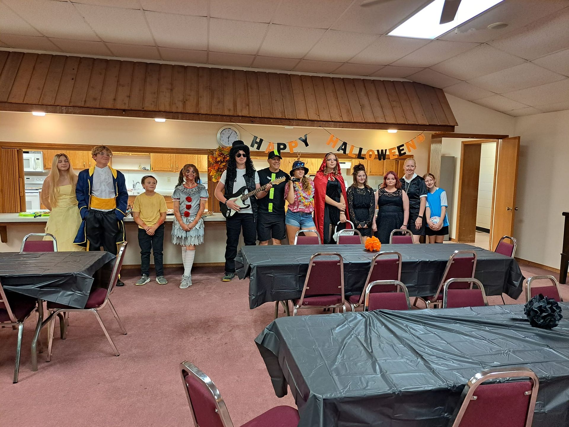 A group of people are standing in a room with tables and chairs.