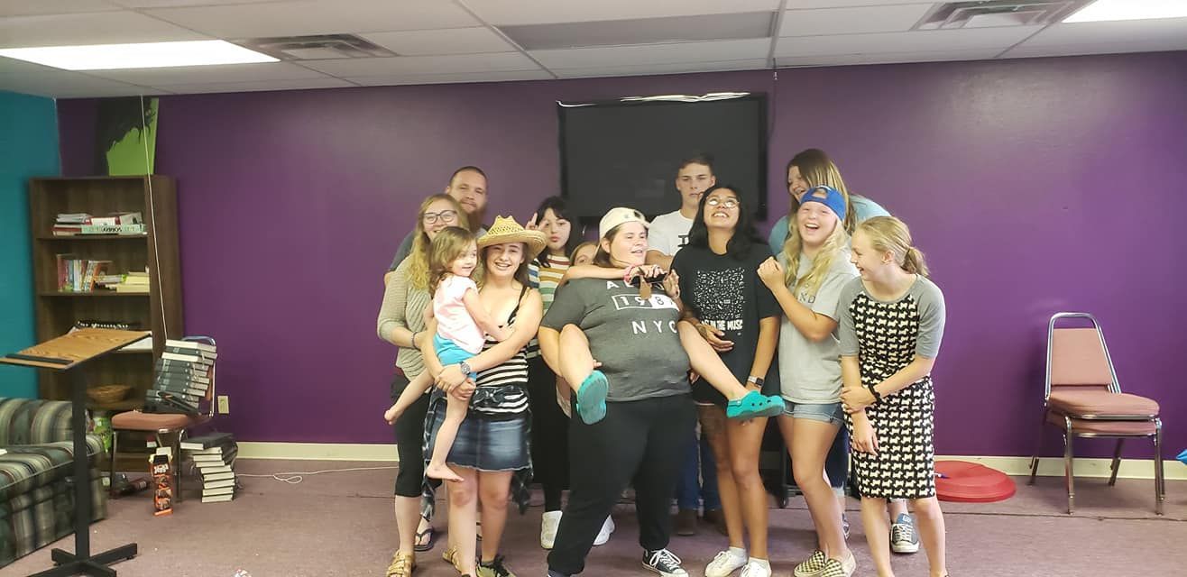 A group of people are posing for a picture in a room with purple walls.