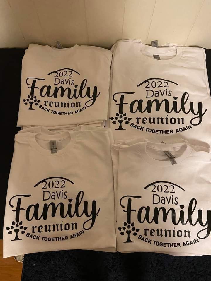 Four white t-shirts with the words `` davis family reunion '' on them are sitting on a table.