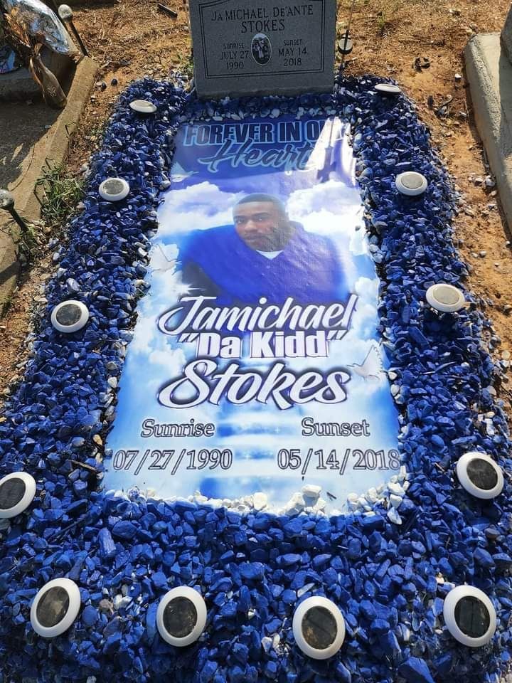 A grave with a picture of a man on it surrounded by blue gravel.