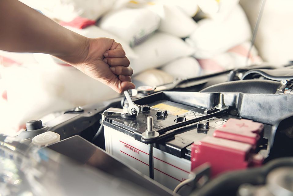 A Person is Fixing a Car Battery With a Wrench — Cessnock Batteries In Bellbird, NSW