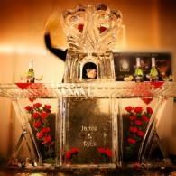 Decorative illuminated altar with crystal sculpture, red roses, and glowing candles in a warm amber setting