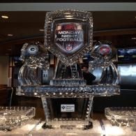 Monday Night Football ice sculpture display with silver helmets on a lit table in a dark room