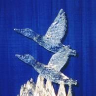Two geese birds in flight against a blue background, above a jagged white form