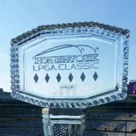 Clear crystal trophy engraved “Thornberry Creek LPGA Classic” against a sky background