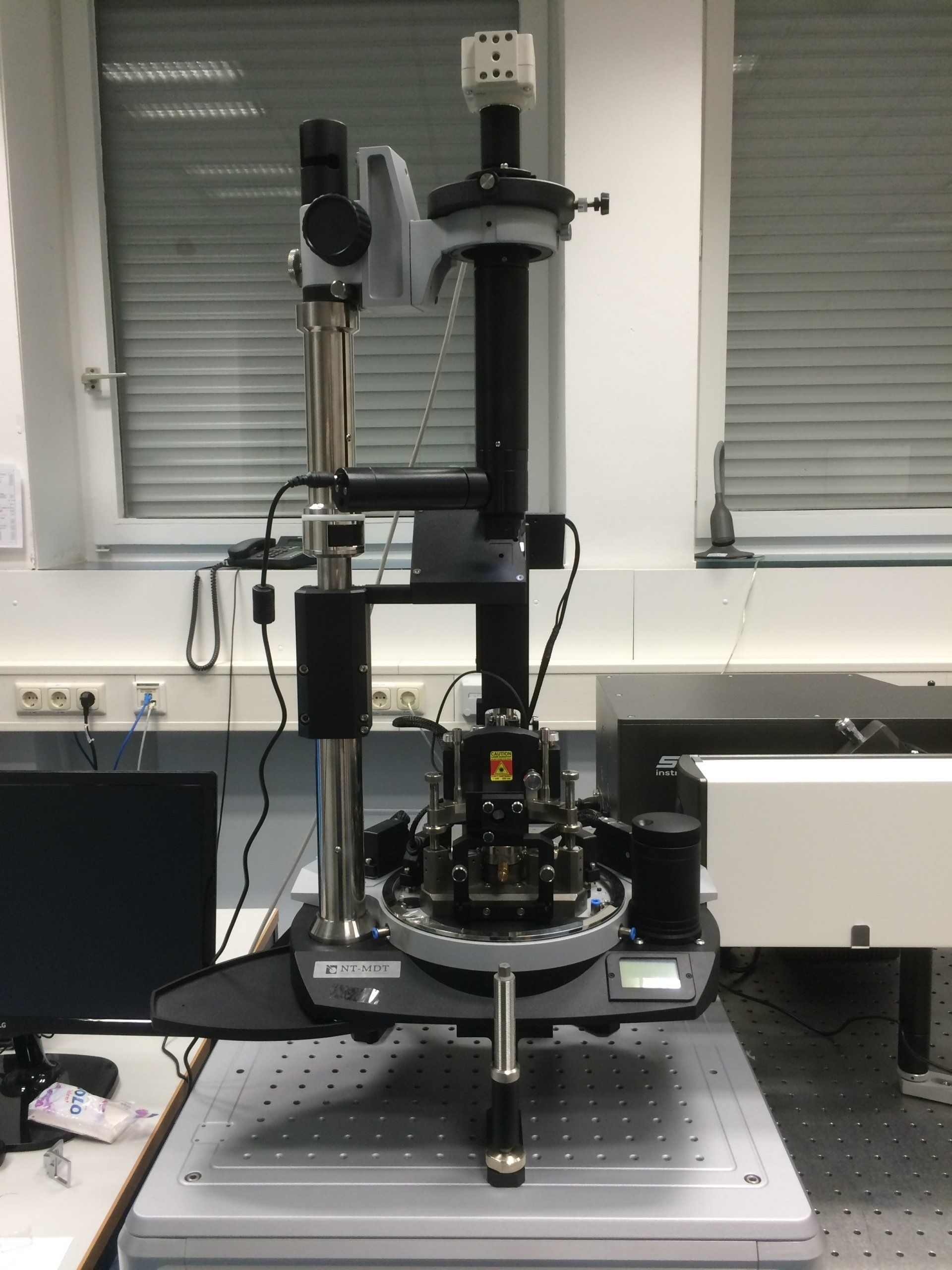 Laboratory setup featuring a vertical precision instrument with connected components and cables in a research environment