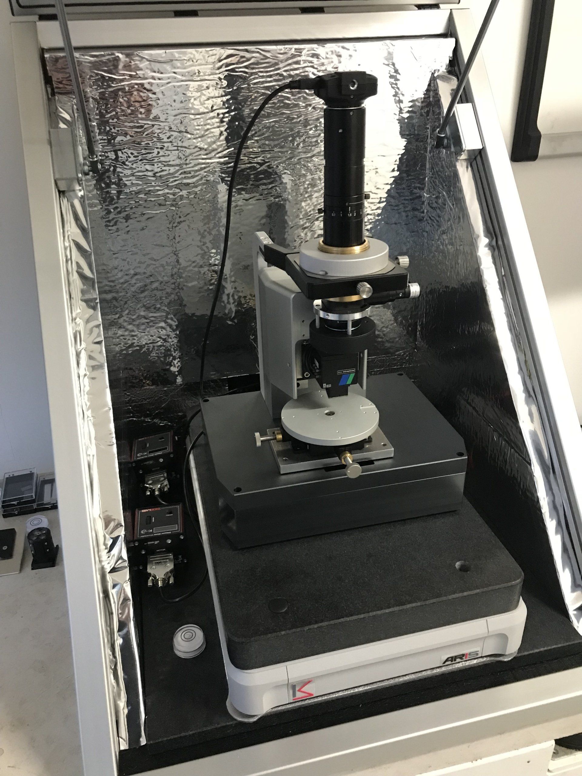 High-precision optical instrument enclosed in a reflective isolation chamber for advanced laboratory analysis