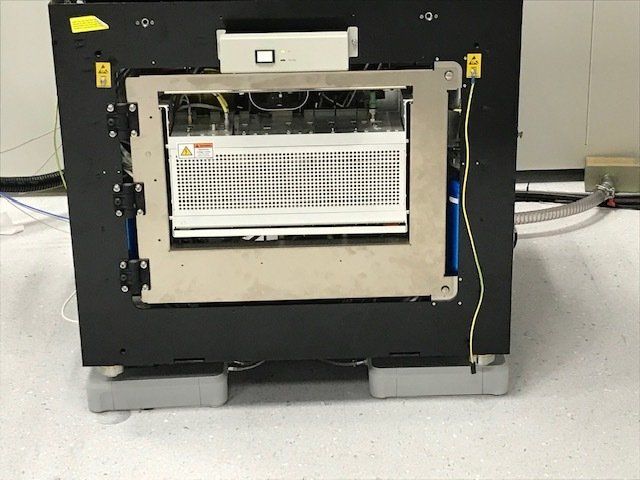 Back view of laboratory equipment with exposed components and wiring in a research environment