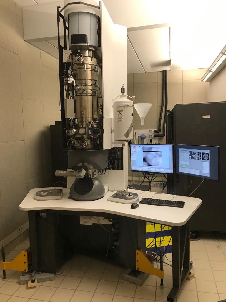 Advanced electron microscope setup with dual monitors displaying analysis data in a laboratory environment