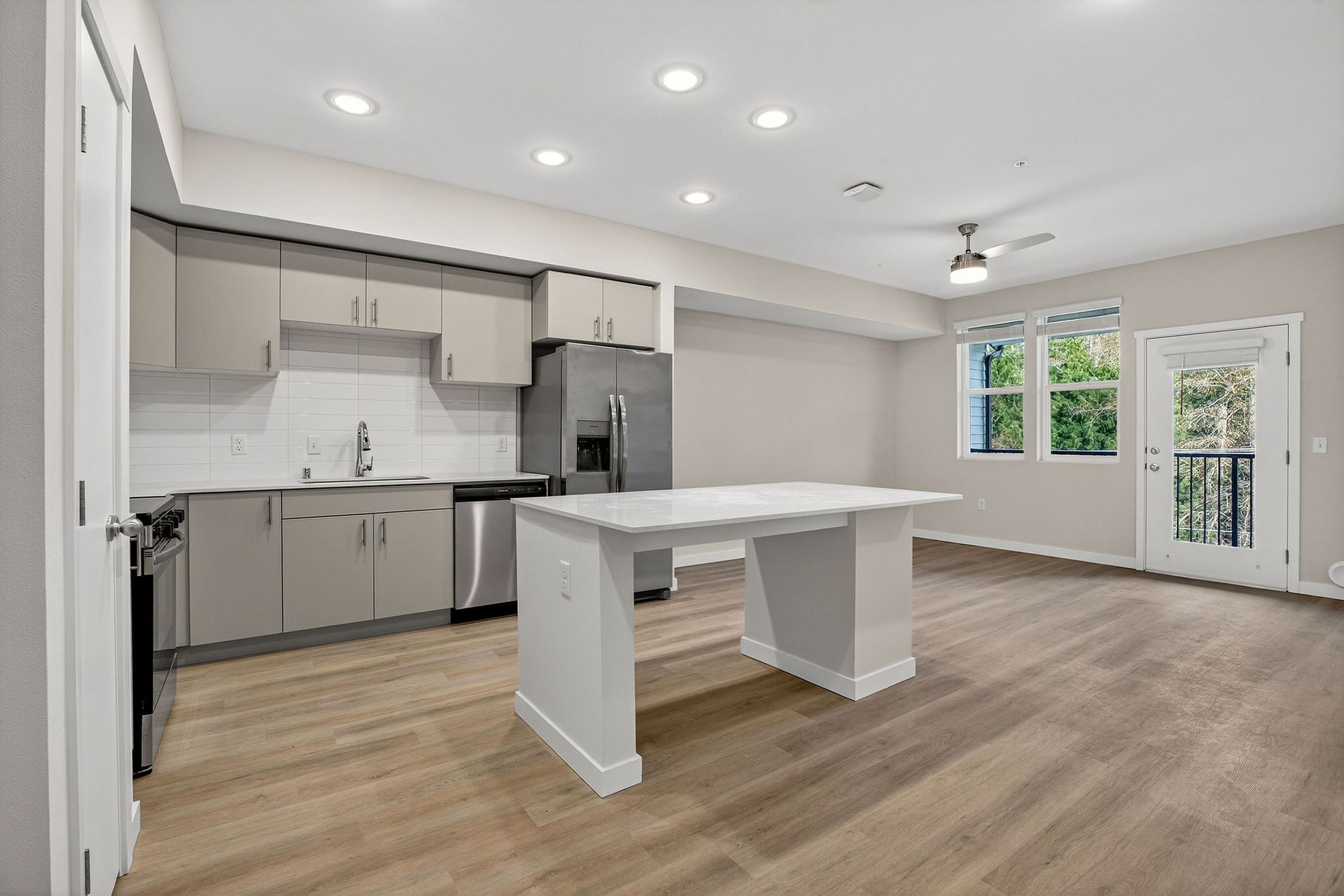 Modern kitchen with island, stainless steel appliances, and light wood floors.