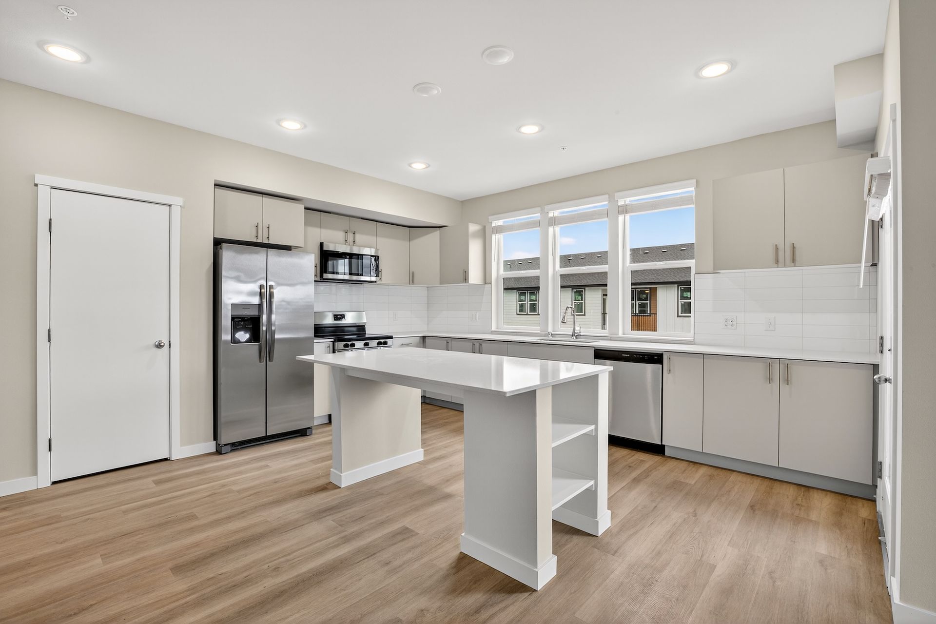 Modern kitchen with stainless steel appliances, white cabinetry, and a central island.