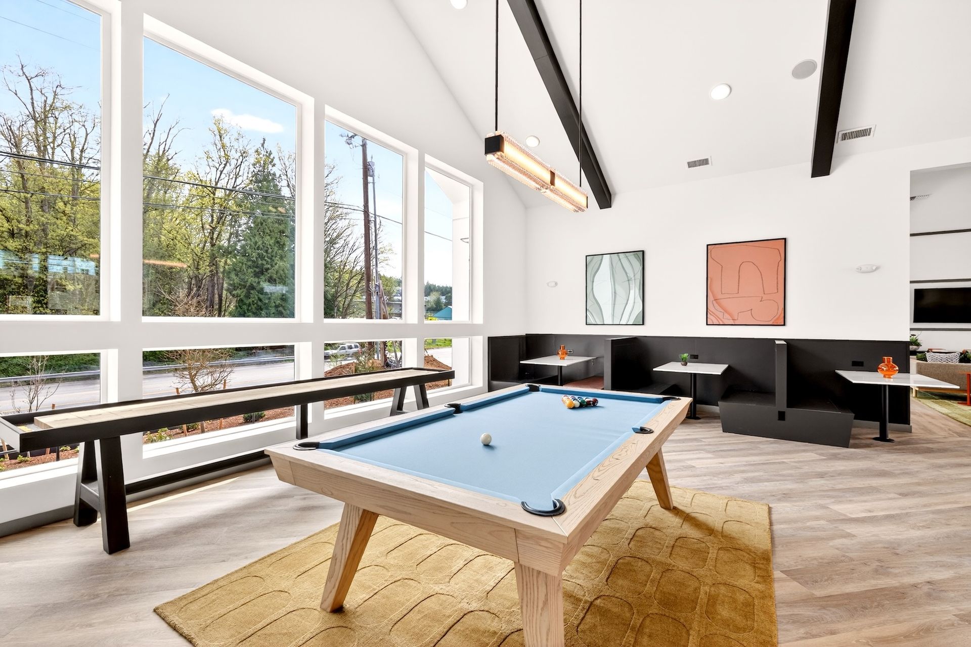 Modern lounge with pool table, floor-to-ceiling windows, and black seating.