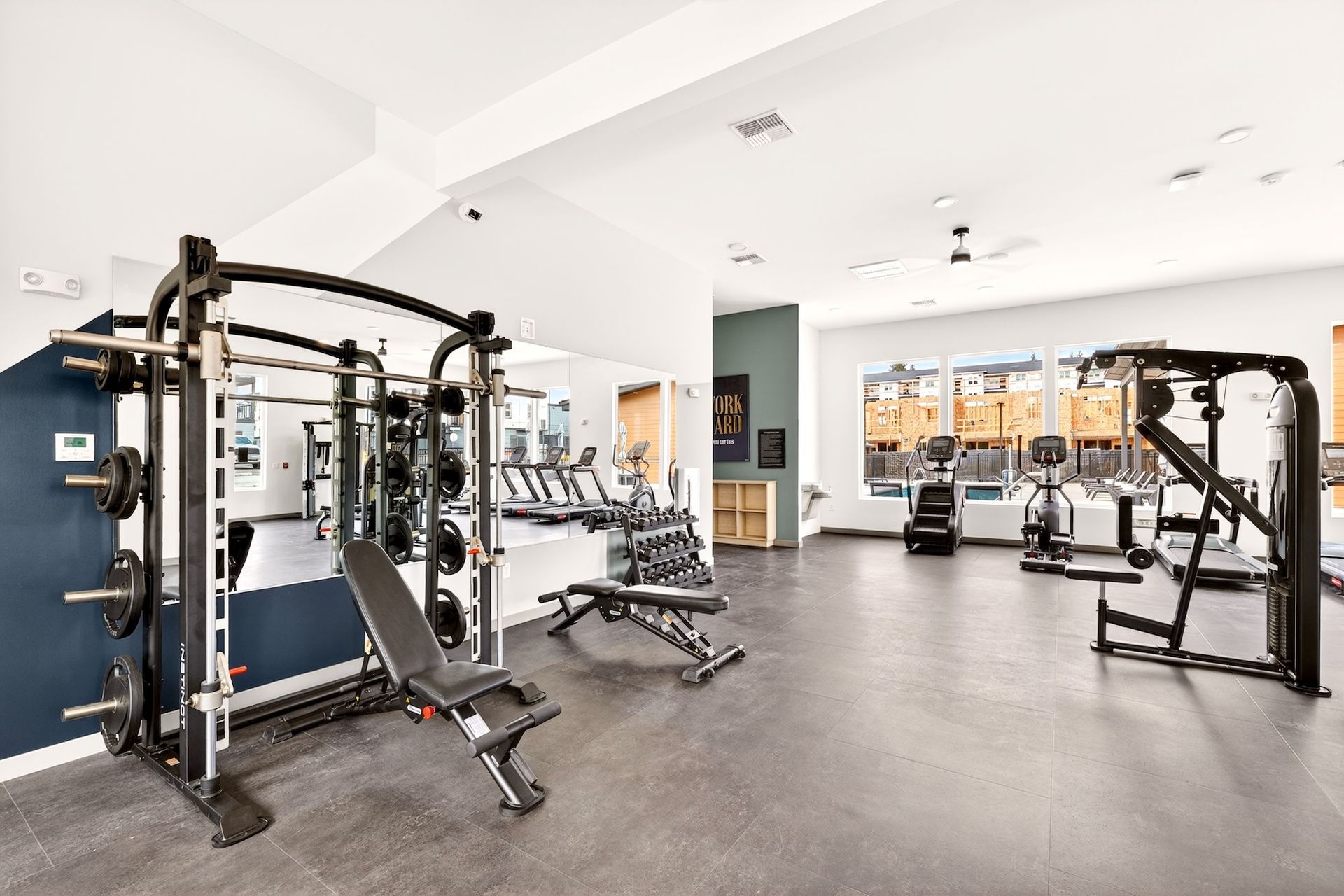 Modern gym interior with weight machines, benches, and large windows