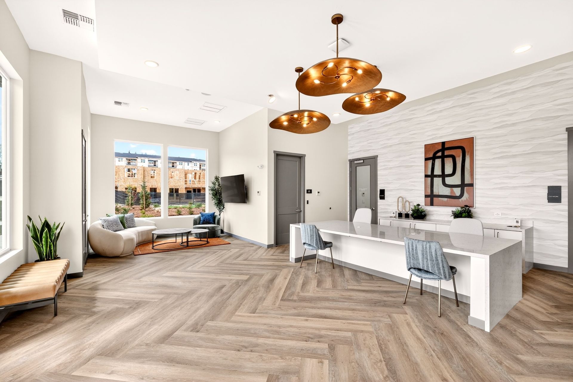 Modern open-plan living room and kitchen with white furniture, wood floors, large windows, and copper pendant lights