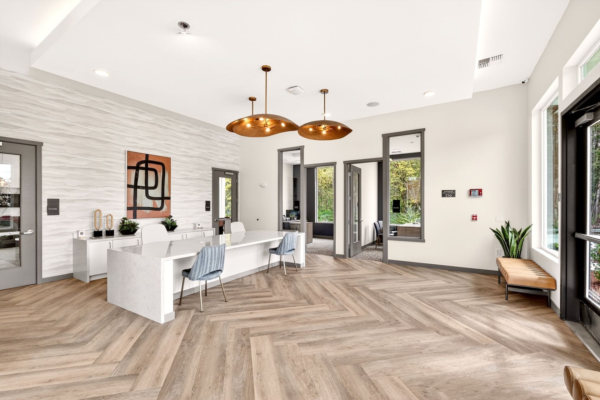 Bright modern living room with white walls, herringbone wood floor, copper pendant lights, and large windows