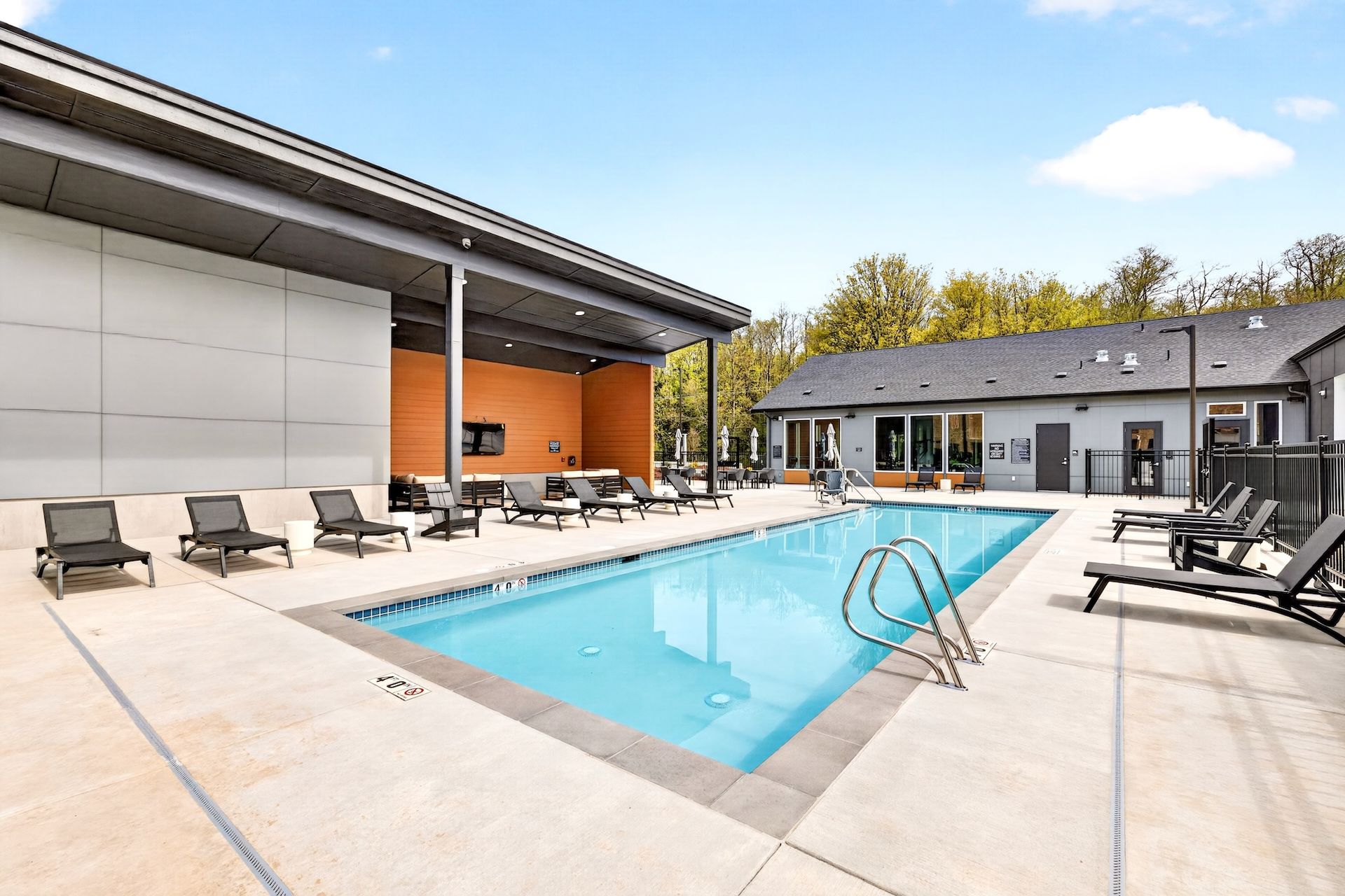 Outdoor swimming pool with lounge chairs and modern buildings under a blue sky
